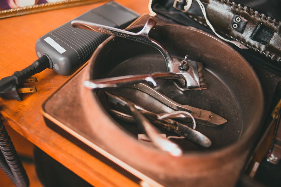 Close-up of vintage barber tools and equipment on a wooden table in a workshop setting.